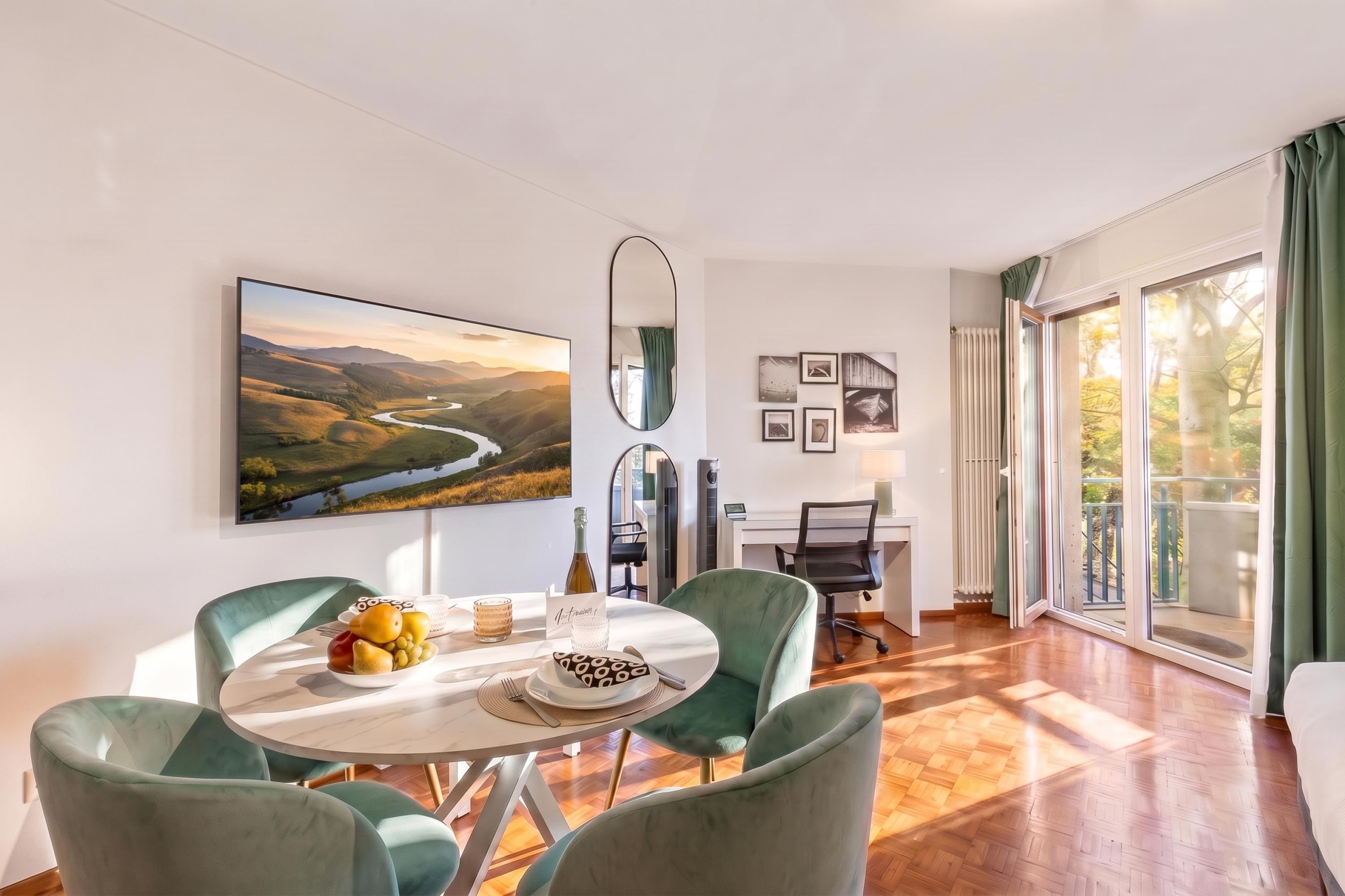 A well-lit room with a dining table set for two, a large landscape painting, and a view through a glass door.