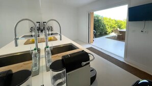 Eine moderne Küche mit großem Fenster, einem eingebauten Backofen und einem an der Wand befestigten Flachbildfernseher.