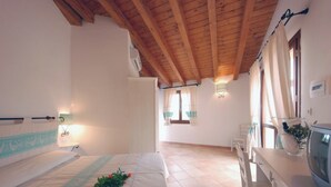 A bedroom with a wooden ceiling, a bed with a floral arrangement, a bedside table, and a television. - Relaxing Residence Baia dei Mirti Studio M3-3 persons-Unit 2 (Province of Sassari)