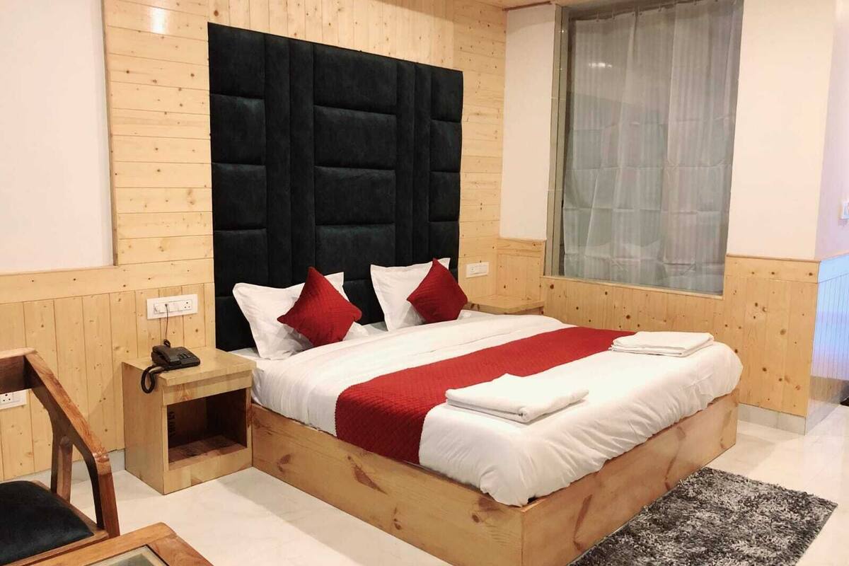 Een slaapkamer met houten lambrisering, een bed, nachtkastjes en een raam met gordijnen.