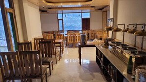 Un comedor amplio con sillas y mesas de madera, una estación de servicio central, y ventanas grandes que ofrecen vistas de la ciudad.