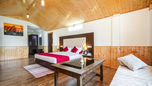 Un dormitorio con una cama grande, techo de madera y una mesita de noche con lámpara.