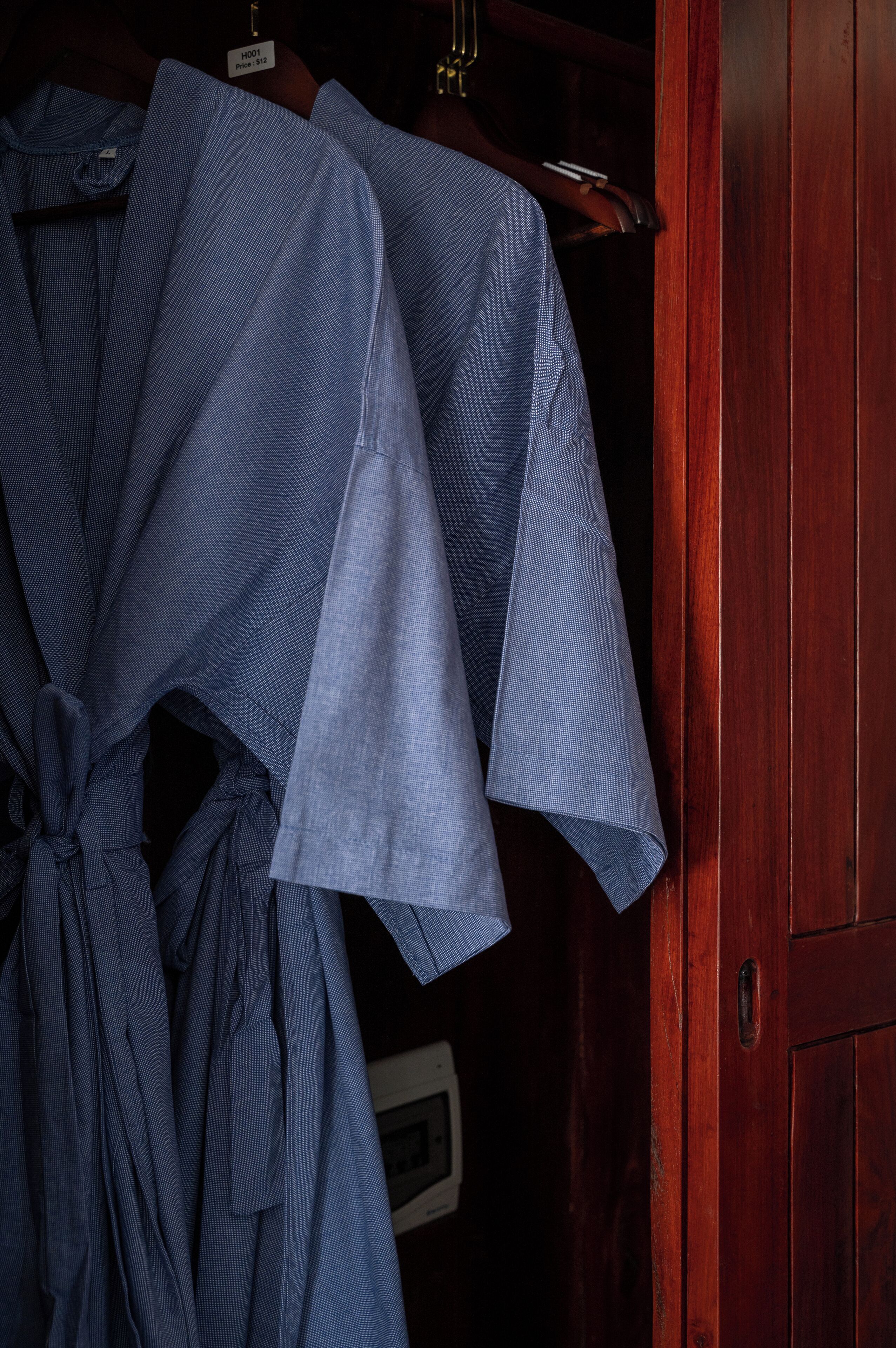 Een houten garderobe met een kledingroede en verschillende kledingstukken.