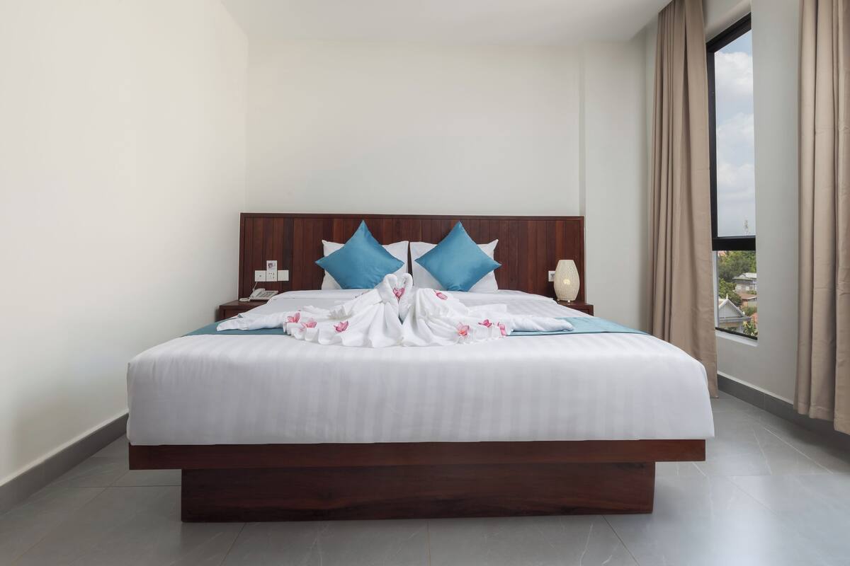 A large bed with a wooden headboard, two blue pillows, and a white bedspread.