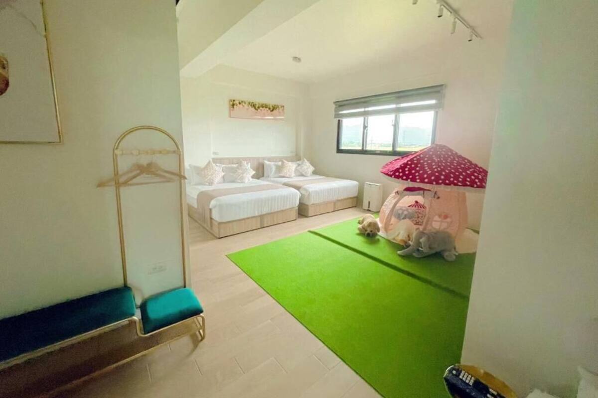 A room with a bed, a green rug, a hanging chair, and a window.