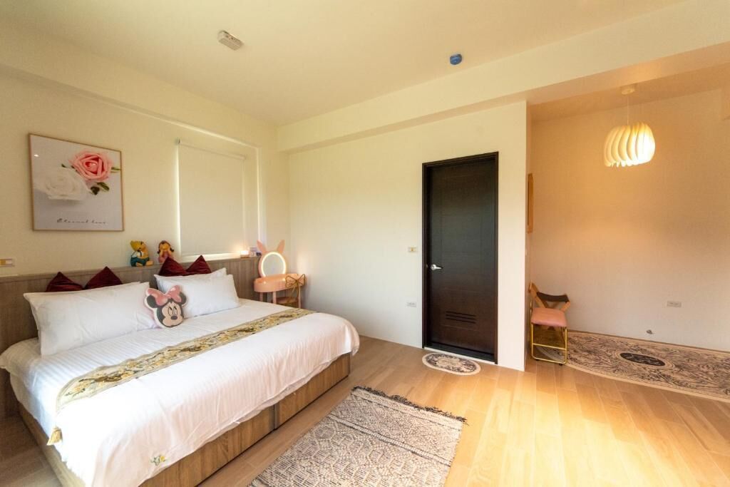 A bedroom with a bed, a bedside table with a lamp, a door, and a chair.