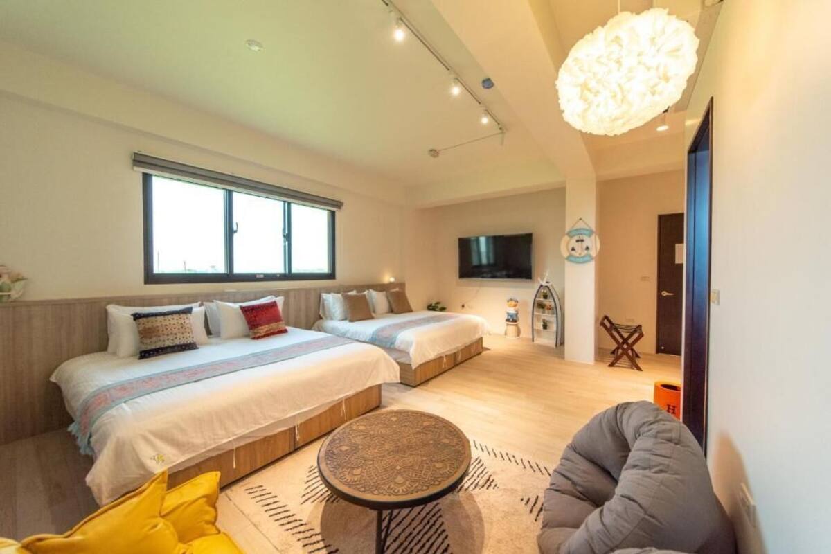 A modern bedroom with two beds, a round coffee table, and a large window.