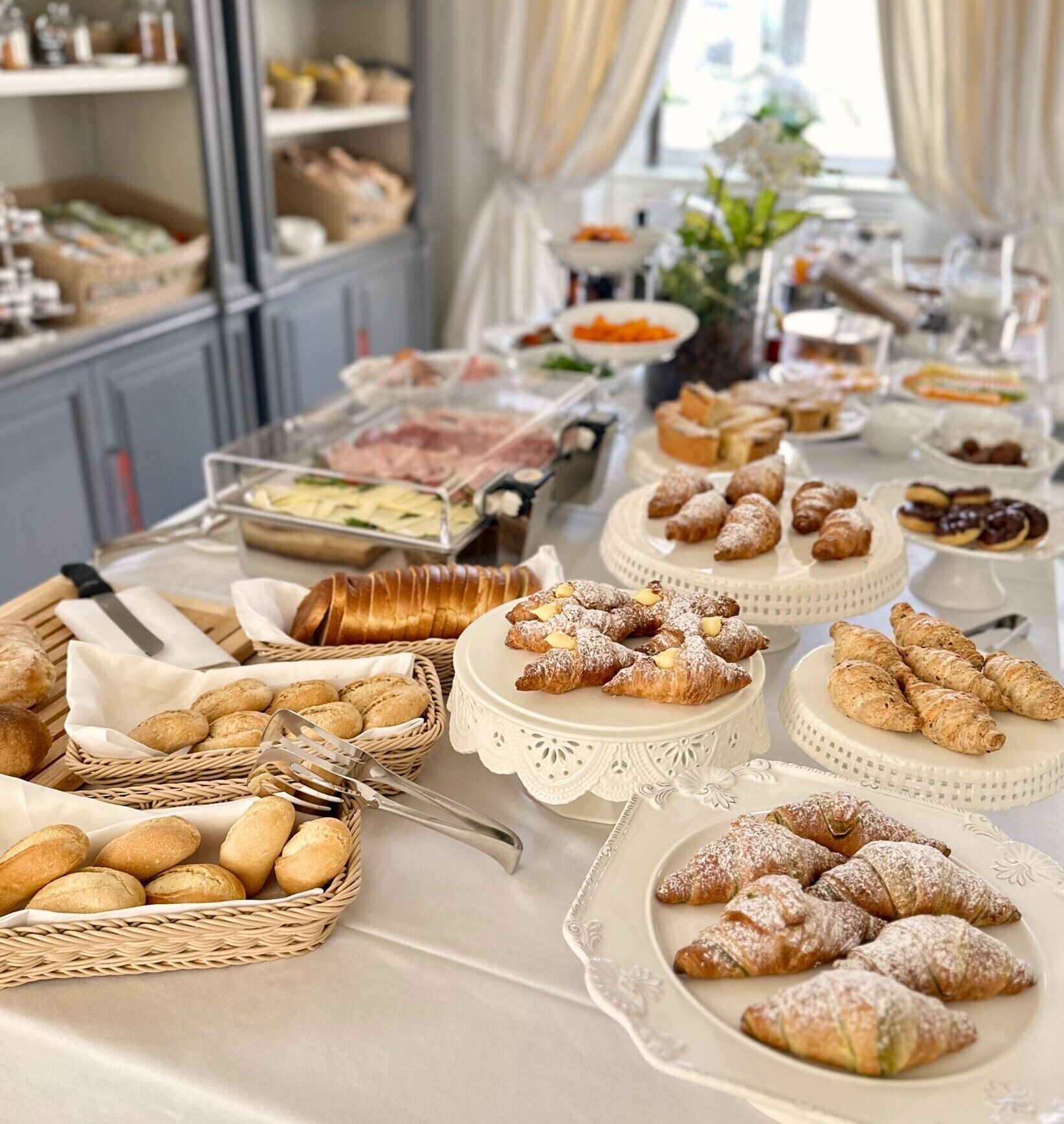 A buffet table with various food items including pastries, bread, and other baked goods.