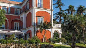 A large, multi-story building with a red and white facade, a pool, and surrounding greenery. - La Tuja Relais du Parc (Vico Equense)