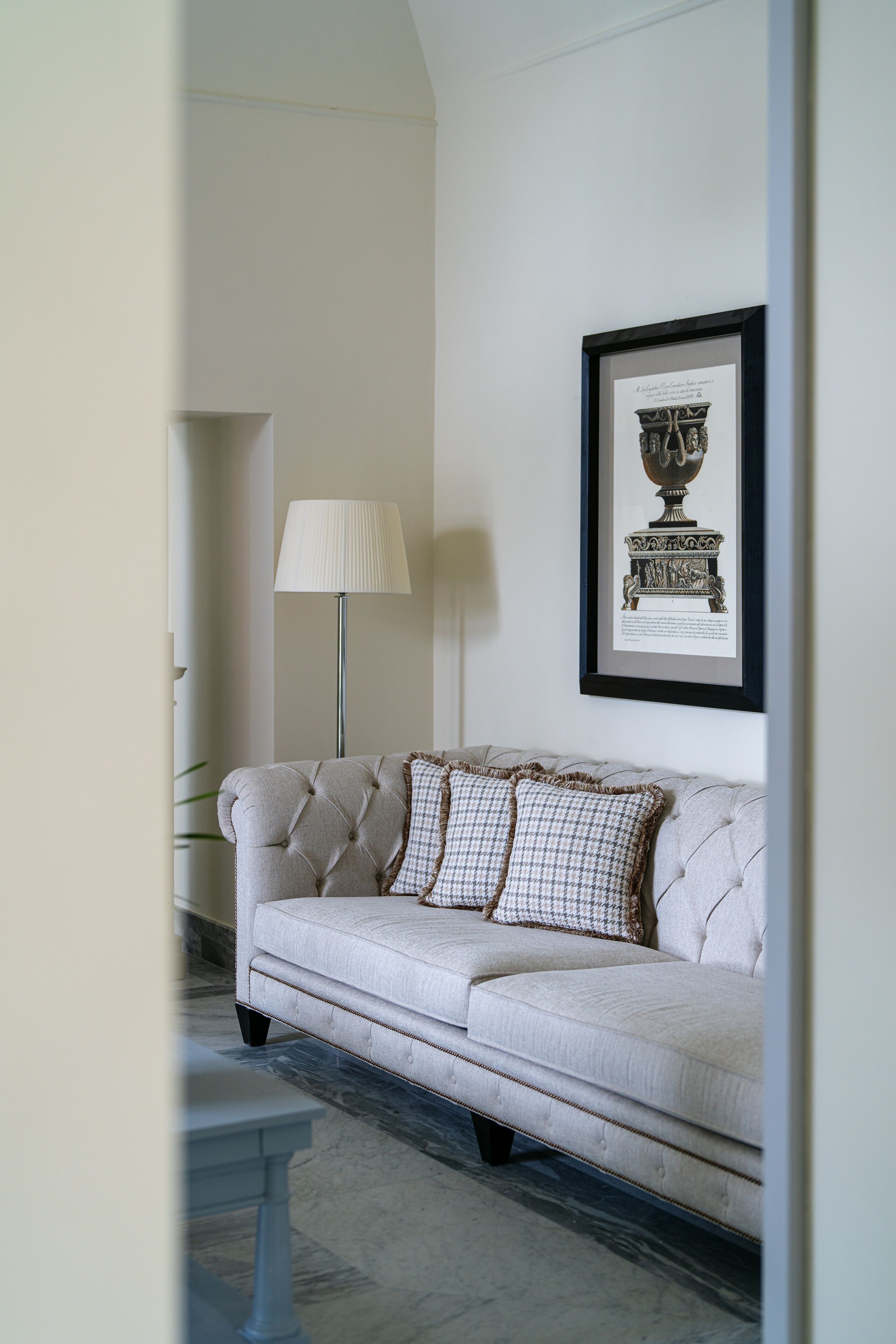 Une pièce avec un canapé blanc, un tableau encadré au mur et un lampadaire.