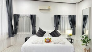 A modern hotel room with a large bed, black curtains, a small table with a lamp, and a potted plant. - phetruntee resort (Sangkhla Buri)
