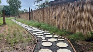 A pathway with circular stepping stones leading to a bamboo fence. - phetruntee resort (Sangkhla Buri)