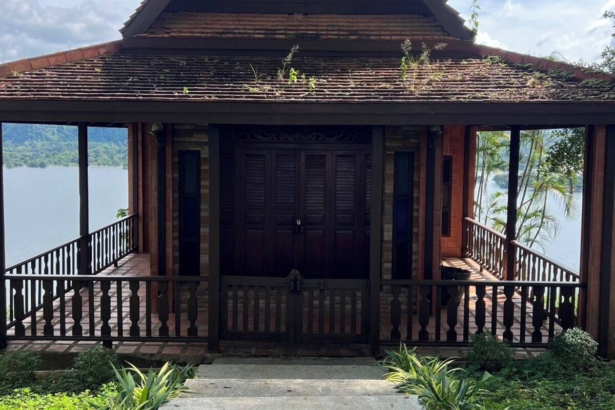 A traditional wooden building with a steeply pitched roof, a central entrance with double doors, and a balcony with a railing.