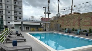 Une piscine sur le toit, dotée de chaises longues et d’un espace salon abrité.