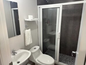 Bathroom features a sink, toilet, and glass-enclosed shower area with a tiled floor.
