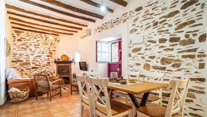 Un'area pranzo rustica con parete in pietra, travi in legno e pavimento piastrellato.
