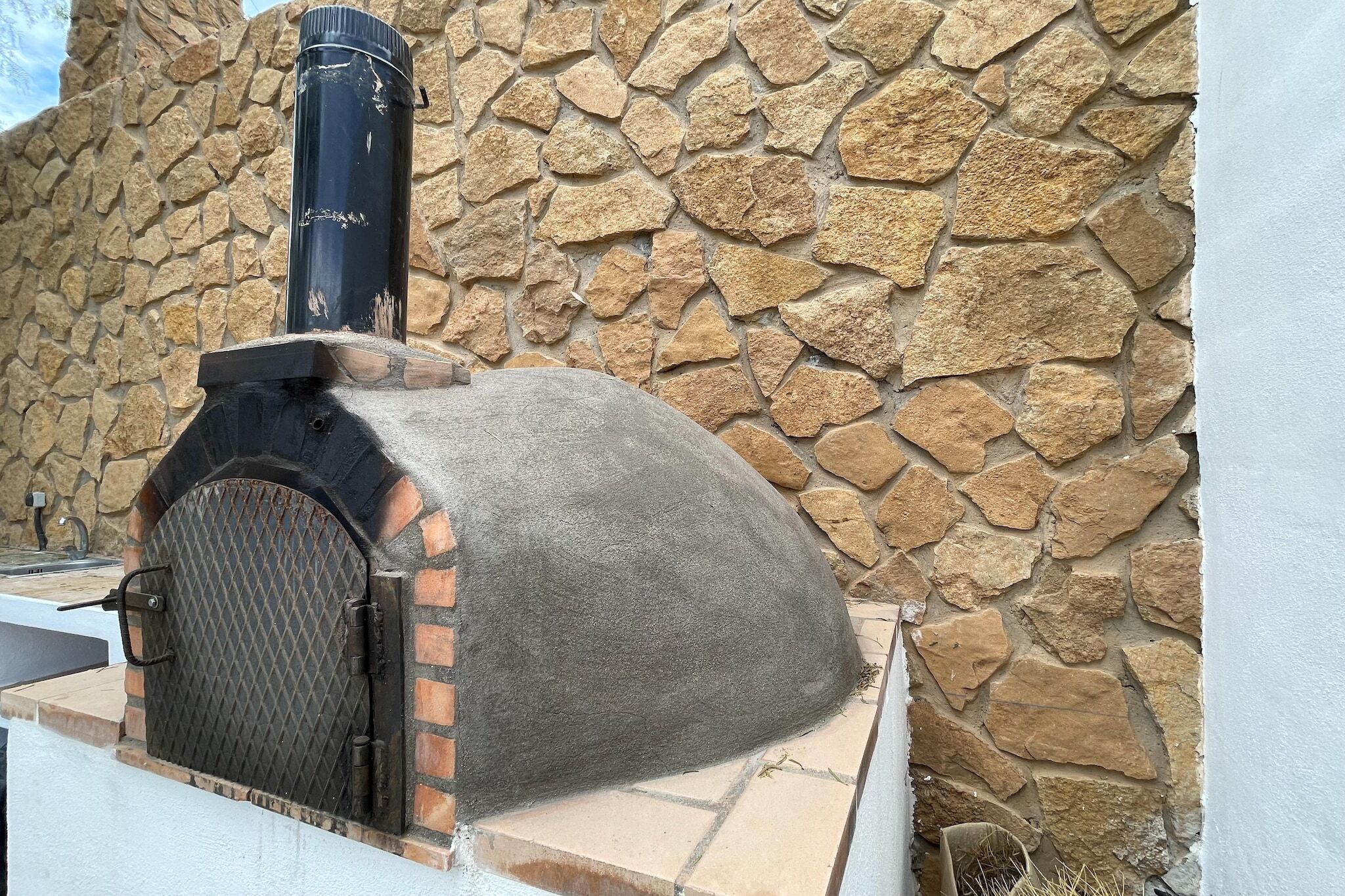 A stone wall with a brick oven and a chimney.