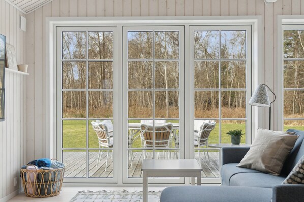 A room with a large sliding glass door leading to an outdoor deck with chairs and a table.