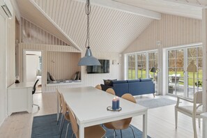Ein modernes Interieur mit einer Essecke, einem blauen Sofa und einem an der Wand montierten Fernseher.