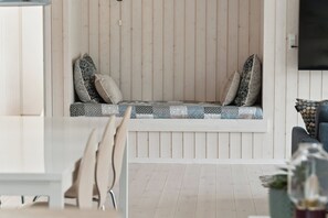 Ein Zimmer mit einer Holzbänkchen, einem Esstisch und einer Couch.