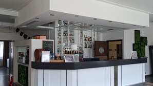 A modern bar area with a counter, shelves of liquor bottles, and a menu board. - Hotel Alpex  (Zabrze)