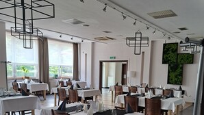A spacious dining area with multiple tables, chairs, and pendant lighting fixtures. - Hotel Alpex  (Zabrze)