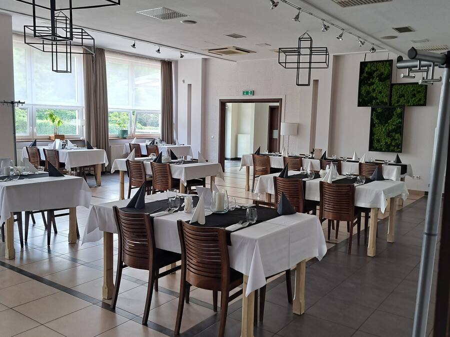 Un comedor amplio con varias mesas, sillas e lámparas colgantes.