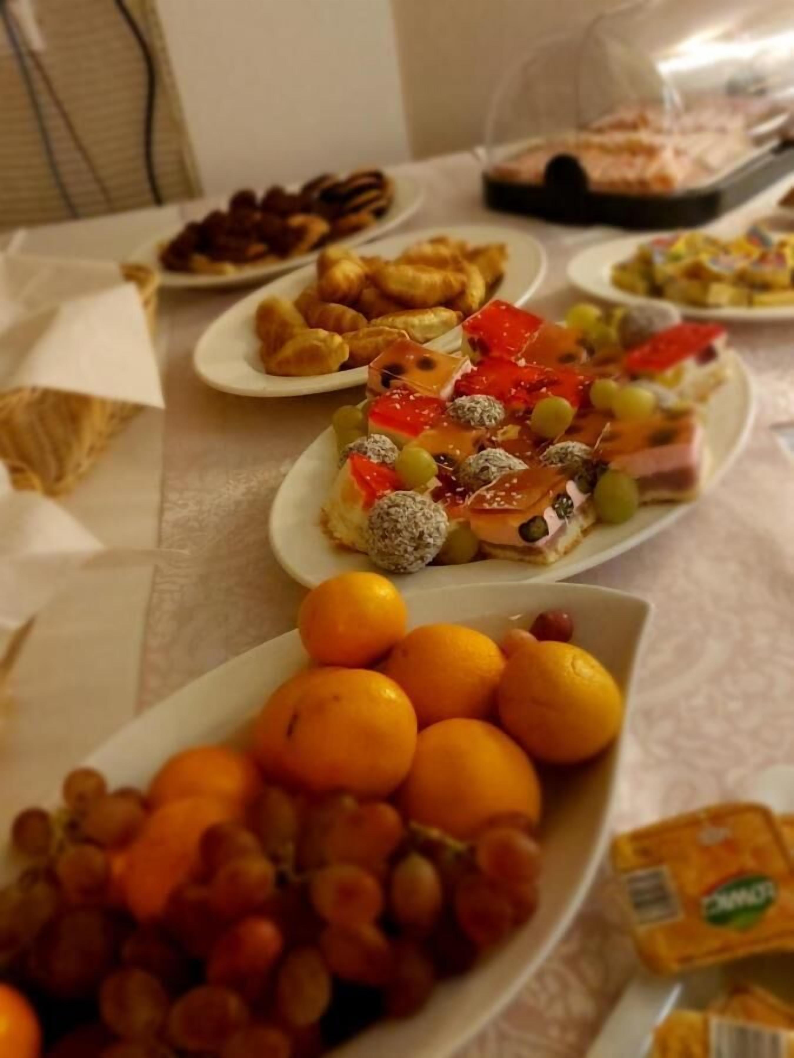 Una mesa de buffet con diversos platos, entre ellos frutas, pasteles y una selección de quesos.