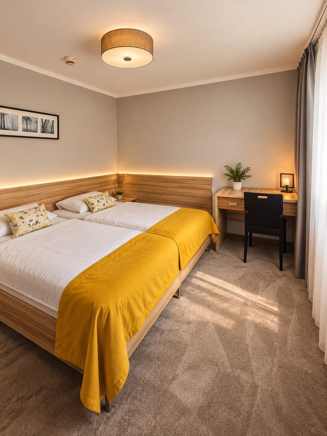 A hotel room with two beds, a desk, a chair, a potted plant, and a framed picture on the wall.