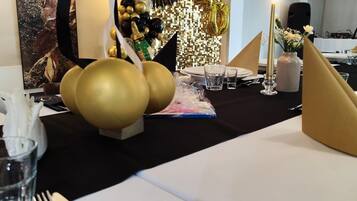 Uma mesa posta para uma celebração, com balões, uma placa com os dizeres '40º Aniversário' e um painel decorativo.