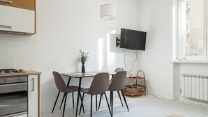 A modern kitchen with a dining area, a flat-screen TV mounted on the wall, and a window providing natural light. - RentPlanet - Apartament Śniadeckich (Warsaw)