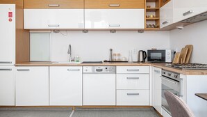A modern kitchen with white cabinets, a built-in microwave, a dishwasher, and a stove. - RentPlanet - Apartament Śniadeckich (Warsaw)