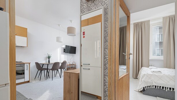 A modern hotel room with a bed, a desk, a chair, a television, and a wardrobe. - RentPlanet - Apartament Śniadeckich (Warsaw)
