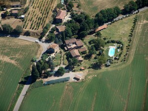 Vista aérea de una propiedad rural con campos en terrazas, una piscina y varias edificaciones.