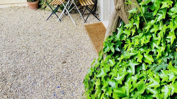 A garden patio with a table and chairs, surrounded by lush greenery and purple flowering vines. - Self-contained apartment in guest house - Near Paris (Meudon)