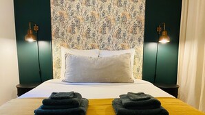 A neatly made bed with two folded towels, a white pillow, and a patterned wallpaper. - Self-contained apartment in guest house - Near Paris (Meudon)