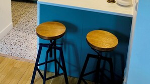 A modern kitchen with a marble countertop, wooden cabinets, and two bar stools. - Self-contained apartment in guest house - Near Paris (Meudon)