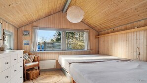 Una habitación con paneles de madera, una cama grande, un tocador, una silla y una ventana con cortinas.