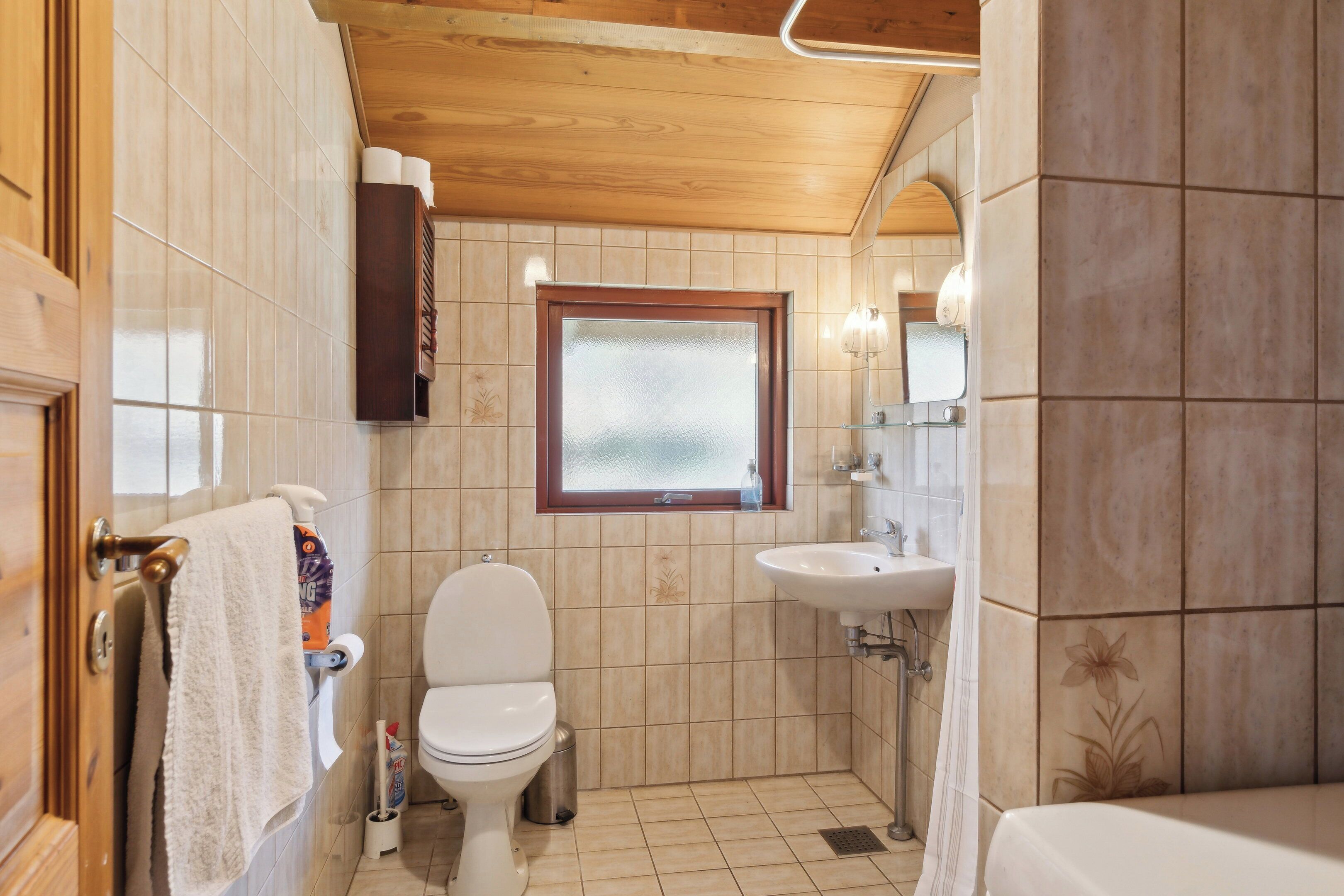A bathroom with a toilet, sink, and window.