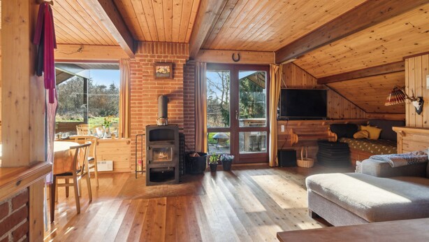 Un interior de cabaña acogedor con chimenea, pisos de madera, un sofá y un comedor.
