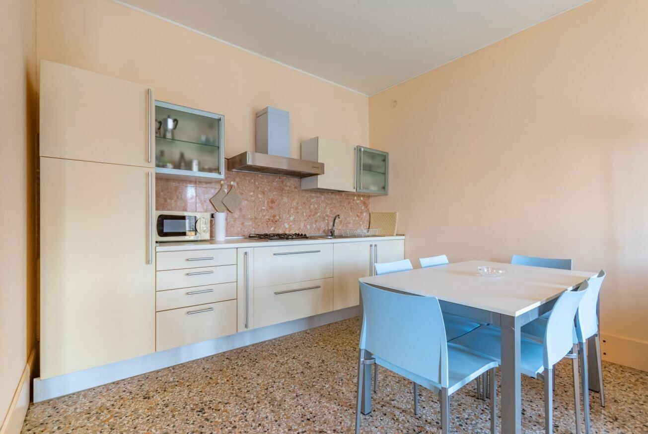 Una cocina compacta con microondas, estufa y alacenas, una mesa de comedor con sillas y una encimera de granito.