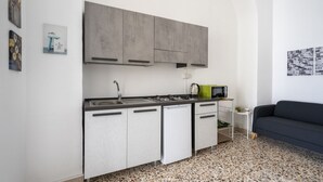 A compact kitchen with a dishwasher, stove, and a small side table with a plant. - GuestHost - Lovely 56 sqm apartment, for 2 people, located on the ground floor of a building (one step to access). The property is located in a central area, less than 10 minutes on foot from the station, in an area full of services and in a strategic po (Catania)