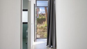 A corridor leading to a balcony with a view of a garden and buildings. - GuestHost - Lovely 56 sqm apartment, for 2 people, located on the ground floor of a building (one step to access). The property is located in a central area, less than 10 minutes on foot from the station, in an area full of services and in a strategic po (Catania)