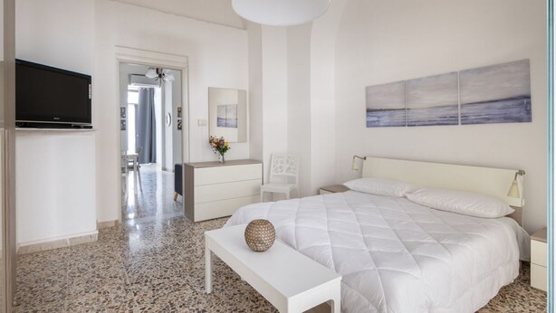 A bedroom with a bed, a television, a desk, and a painting on the wall. - GuestHost - Lovely 56 sqm apartment, for 2 people, located on the ground floor of a building (one step to access). The property is located in a central area, less than 10 minutes on foot from the station, in an area full of services and in a strategic po (Catania)