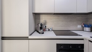 A modern kitchen with white cabinets, a built-in stove, and a coffee machine. - GuestHost - In the heart of Bergamo, a cozy 45 sqm apartment for 3 guests, located on the third floor with an elevator (not suitable for disabled persons). Its central location allows you to fully experience the city, with shops, restaurants, and service (Bergamo)