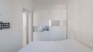 A modern hotel room with a large bed, a wardrobe, and a small kitchenette area. - GuestHost - In the heart of Bergamo, a cozy 45 sqm apartment for 3 guests, located on the third floor with an elevator (not suitable for disabled persons). Its central location allows you to fully experience the city, with shops, restaurants, and service (Bergamo)