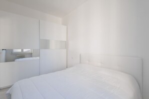 Une chambre moderne avec un grand lit, une armoire intégrée et une fenêtre.