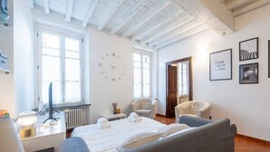 A bedroom with a bed, two chairs, a desk with a computer, a clock, and framed pictures on the wall. - Comfortable 55 sqm apartment in the heart of Parma. The accommodation, which can host up to 4 guests, is located on the first floor of a period building without lift. Please note that there is one step to access the building and stairs to reach the apart (Parma)