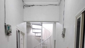 Un corridoio con pareti bianche, una scala a chiocciola bianca e pavimento piastrellato.