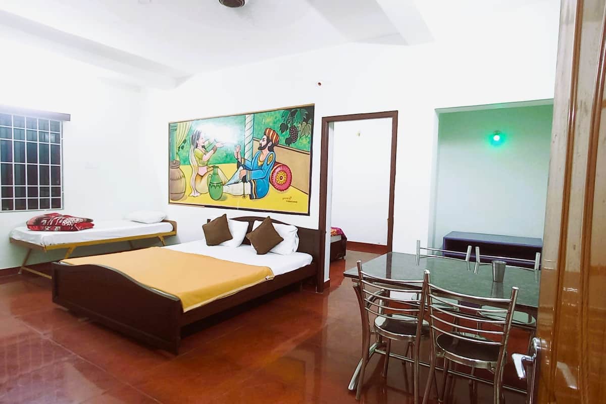 A room with a bed, a dining table with chairs, a window, and a painting on the wall.